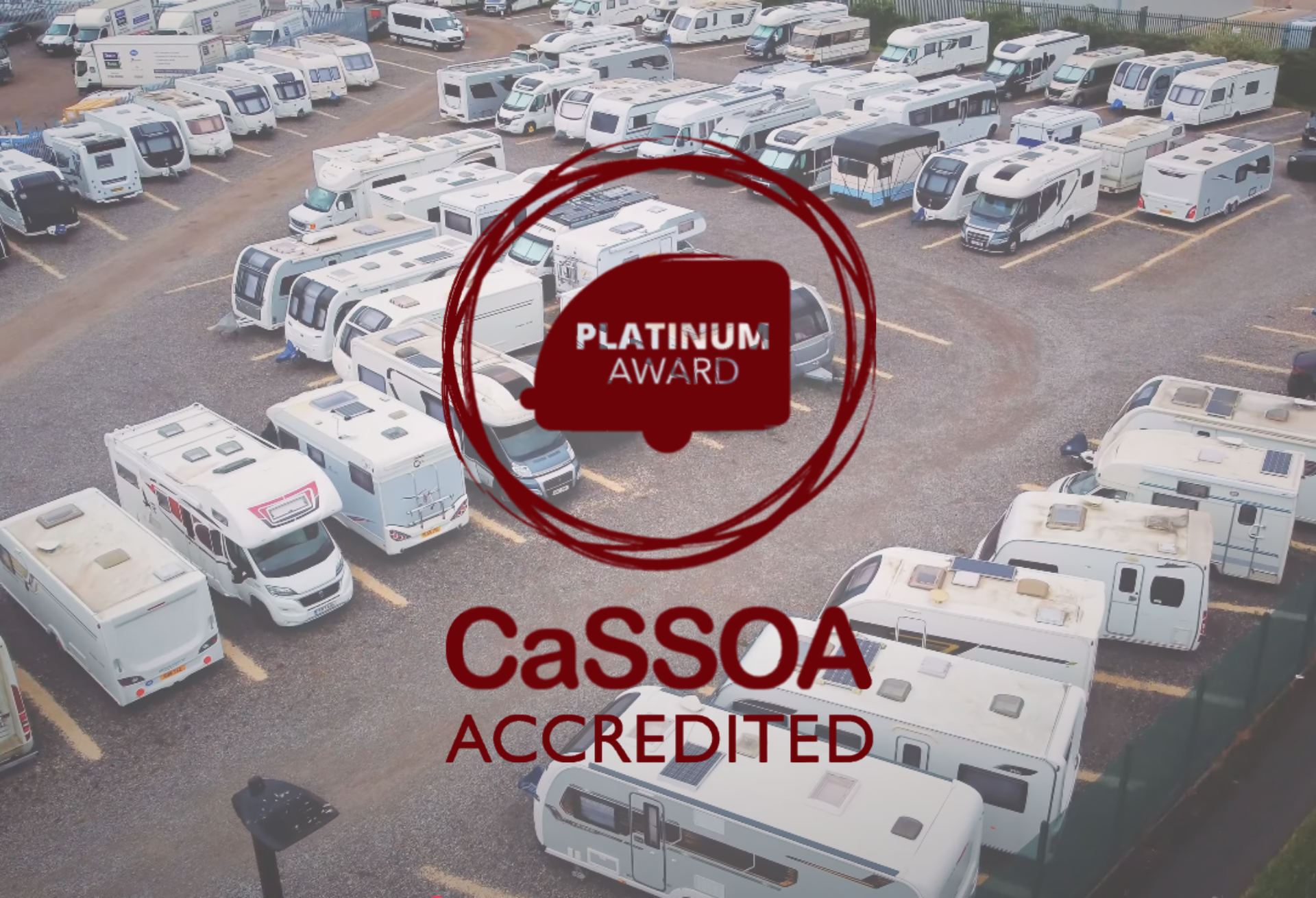 Wide view of a well-lit caravan storage compound with CCTV cameras and perimeter fencing at dusk
